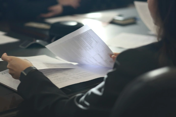 a woman sitting at a table reading a paper